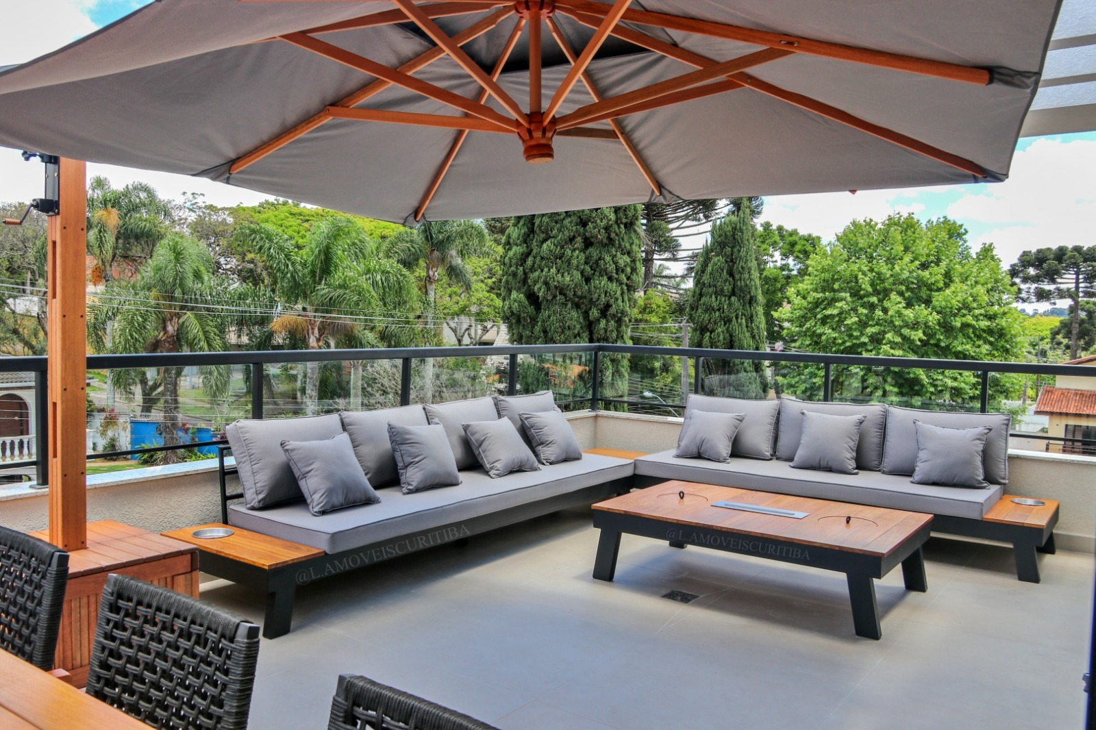 Lounge outdoor com sofás modulares sob ombrelone em varanda com vista para a mata