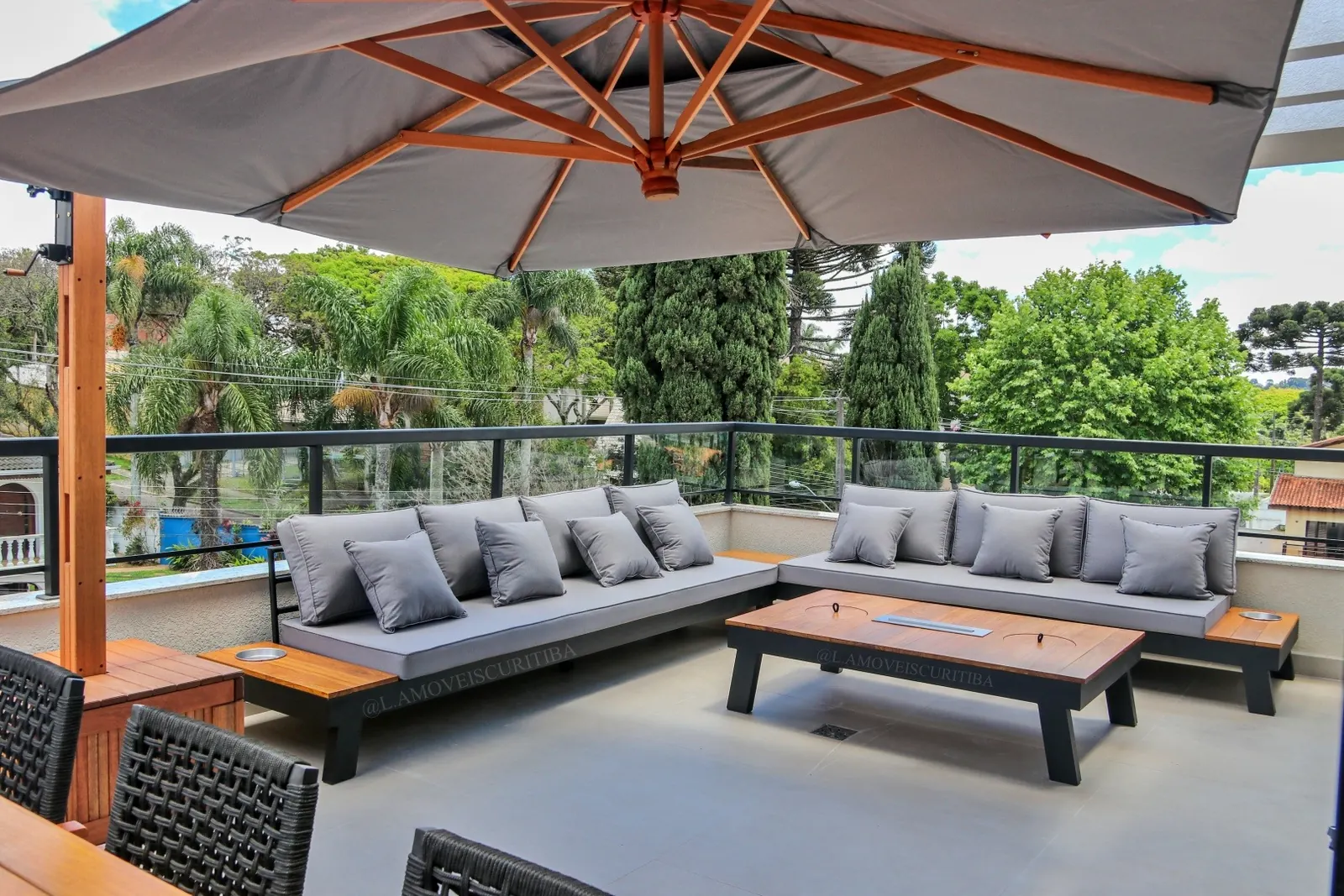 Cobertura com sofá modular cinza, ombrelone de madeira e mesa de centro em Cumaru com vista para as árvores