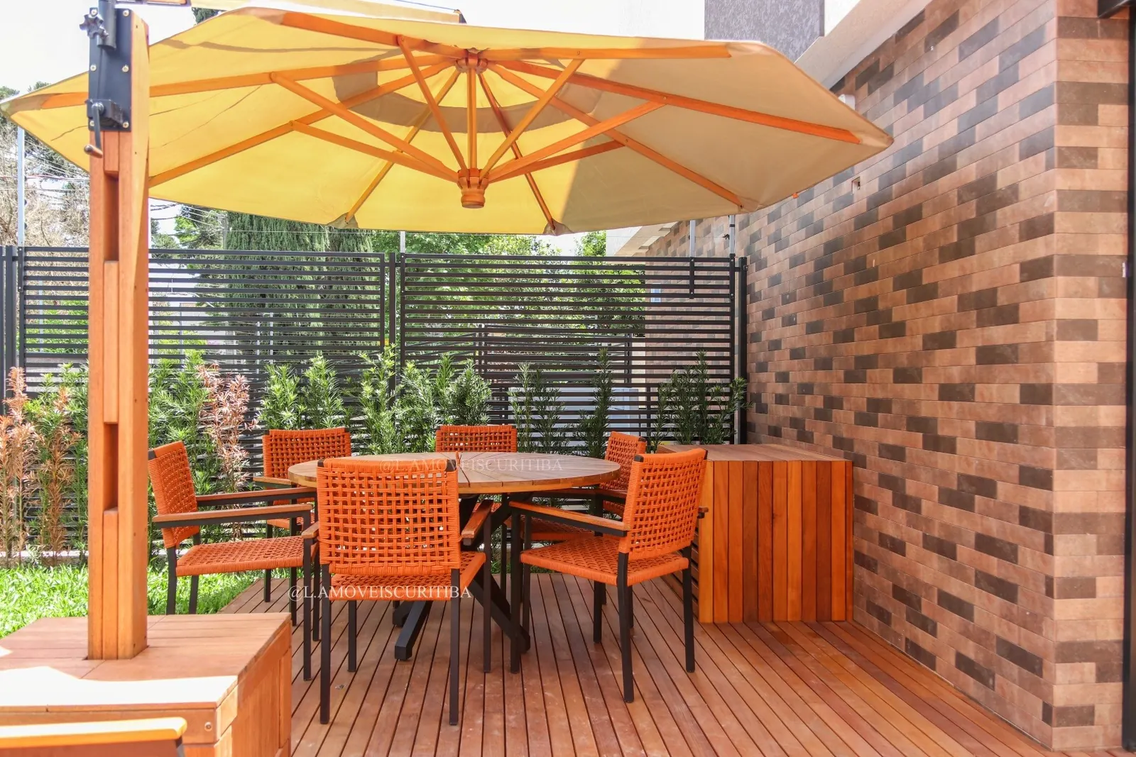 Deck com mesa de jantar redonda, cadeiras em corda náutica laranja e ombrelone bege
